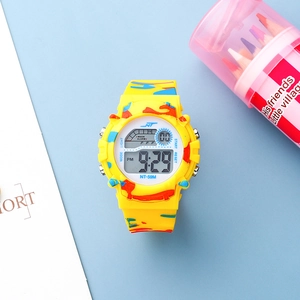 Kids digital watch with yellow camouflage strap and LED backlight display on blue desk