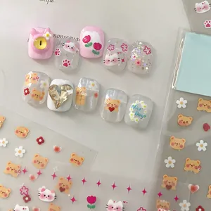 Detail of pink cartoon bear press-on nails with 3D heart crystal and matching stickers