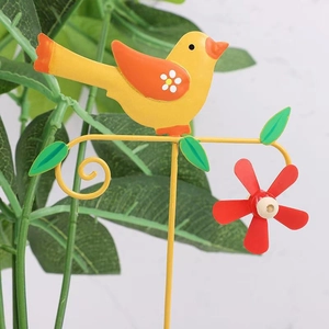 Dettaglio ravvicinato di uccellino giallo e fiore rosso su picchetto da giardino