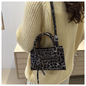 Dettaglio della mini borsa leopardata stile biker indossata da modella con tracolla