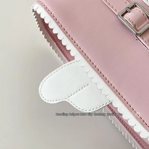 Detail of pink faux leather bag with white wavy scalloped edges and a heart-shaped charm
