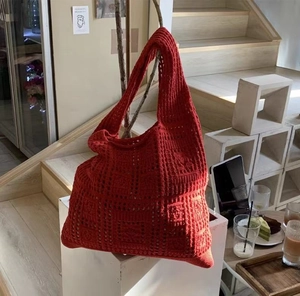 Close-up of red hollow crochet knit shoulder bag showing texture and large capacity