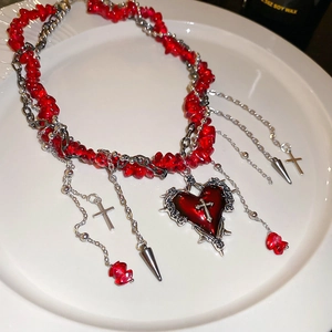 Detailansicht der Gothic-Halskette mit roten Steinen und Herz-Kreuz-Anhänger auf weißem Teller