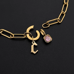 Nahaufnahme einer goldfarbenen Edelstahlkette mit rosa Edelstein und C-Anhänger.