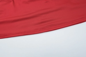 Detailed close-up of double-stitched hem on red V-neck dress made of smooth knit fabric