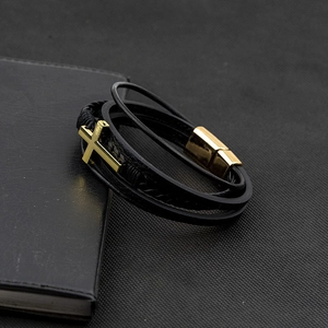 Detail of multi-layer black leather bracelet with golden cross and magnetic clasp