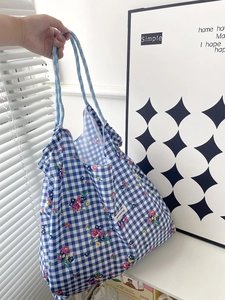Detail of floral blue checkered canvas tote bag with Have a Nice Day woven label