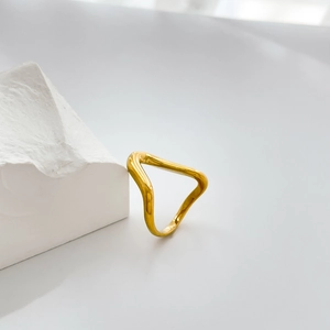 Detailed view of an 18K gold minimalist curved wave ring on a white geometric block