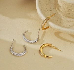 Close-up of gold and silver S925 C-shaped earrings with micro-pave cubic zirconia crystals
