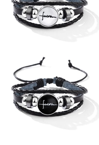 Close-up of multilayer braided leather faith bracelets with black and white pendants