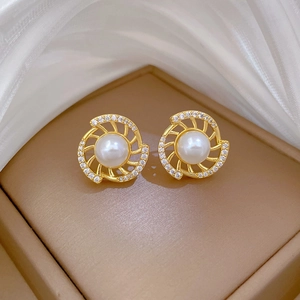 Macro view of luxury pearl earrings with spiral gold frame and pave crystals