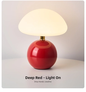 Close-up of a Nordic mushroom lamp with a dark red base and warm yellow light