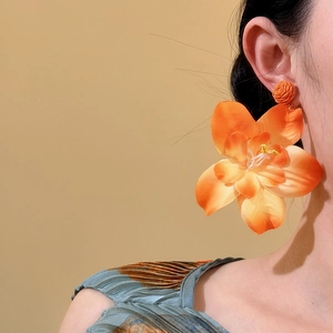 Primer plano de pendientes colgantes de flores de rafia naranja llevados por una modelo