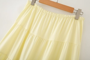 Detail of light yellow tiered cotton skirt showing the elastic waistband and woven fabric