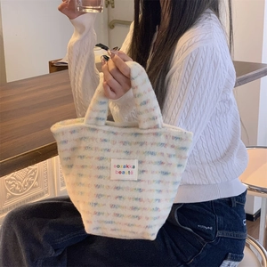 Close-up of small plush tote bag with colorful stripes and woven sozakka label