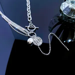 Detail of layered silver necklace featuring a pearl pendant and vintage embossed coin