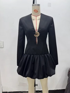 Détail de mini robe noire avec décolleté en V, boucle dorée et jupe ballon bouffante