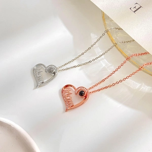 Silver and rose gold heart necklaces with 'Mom' lettering and 100 languages projection stone
