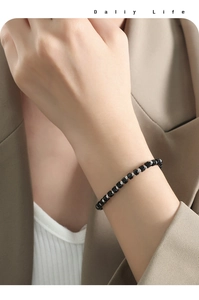 Dettaglio di un bracciale minimalista con cubi neri e perline d'argento sul polso