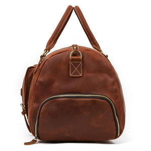 Detail view of the side zipper pocket and vintage brown leather texture on a travel duffel