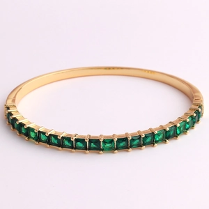 Close-up of 18K gold-plated bangle with square emerald-cut green cubic zirconia stones