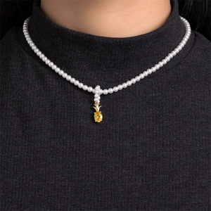 Close-up of pearl necklace with gold pineapple pendant on a charcoal turtleneck sweater