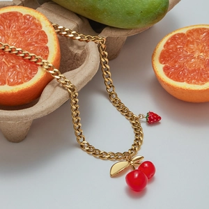 Chic gold titanium necklace with red cherry and strawberry charms on a creative fruit set