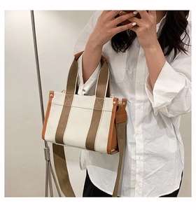 Detail of canvas tote bag with brown leather trim and adjustable shoulder strap