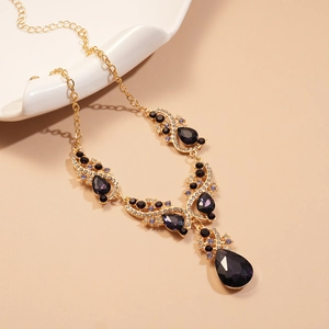 Detailed view of teardrop rhinestone necklace with purple stones and gold hollow pattern