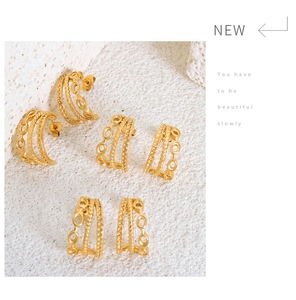 Macro detail of triple-layer C-shaped gold hoop earrings with twisted thread texture