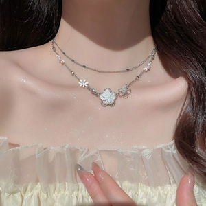 Close-up of a silver double-layer necklace with white floral pendants and pearls