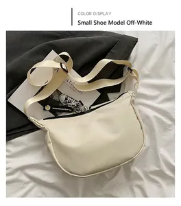 Detail of off-white crescent crossbody bag with mini shoe charm and daisy woven strap
