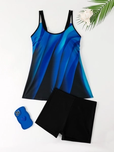 Flat lay of blue abstract print tankini swimsuit with black swim shorts on beach background