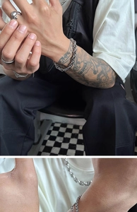 Close-up of hip-hop silver titanium steel link bracelets and rings on a tattooed male wrist