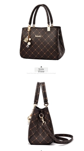 Detail of brown patterned handbag featuring gold logo and decorative floral pearl charm