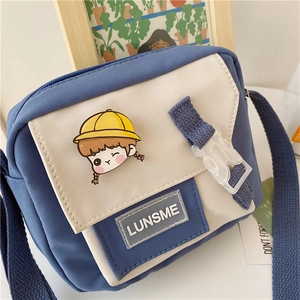 Detail of canvas crossbody bag showing blue and beige patchwork with cartoon patch