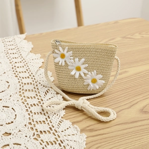 Detail of straw crossbody bag for children featuring white daisy flowers and cotton rope strap