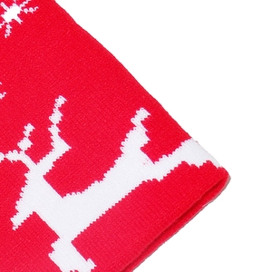 Close-up of red and white knitted fabric showing reindeer patterns and detailed texture