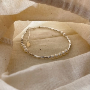 Elegant S925 silver beaded bracelet with white pearls on minimalist linen bag