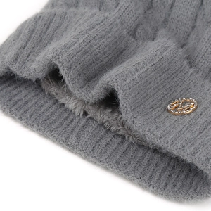 Détail d'un bonnet gris en tricot avec doublure polaire épaisse et logo en métal doré