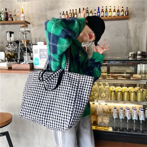 Detailed view of a large black and white checkered canvas tote bag with woven handles