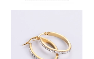 Close-up of golden oval hoop earrings with sparkling rhinestones and snap closure