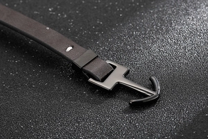 Vue macro du fermoir ancre en métal noir sur un bracelet en cuir tressé marron foncé