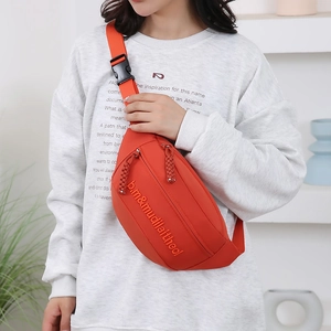 Bright orange casual canvas crossbody bag worn by a model in a modern home setting