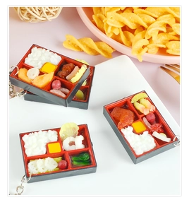 Close-up of a miniature food keychain showing realistic bento box details and accessories