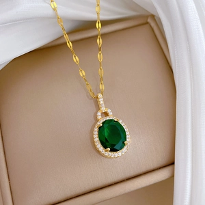 Gros plan d'un collier en acier titane avec pendentif goutte en zircon vert doré