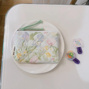 Macro detail of quilted floral coin purse with zipper puller on white porcelain plate