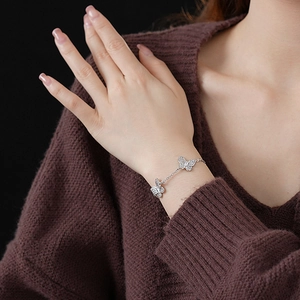Close-up of a silver butterfly charm bracelet with sparkling zircon stones on a wrist