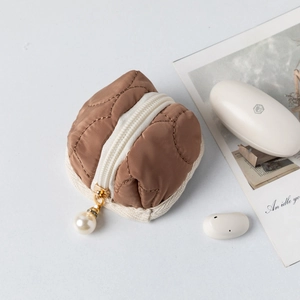 Detailed macro of brown quilted earphone case with elegant pearl zipper charm and padding