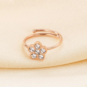Close-up of rose gold cat paw ring with flower zircon inlay on soft fabric background